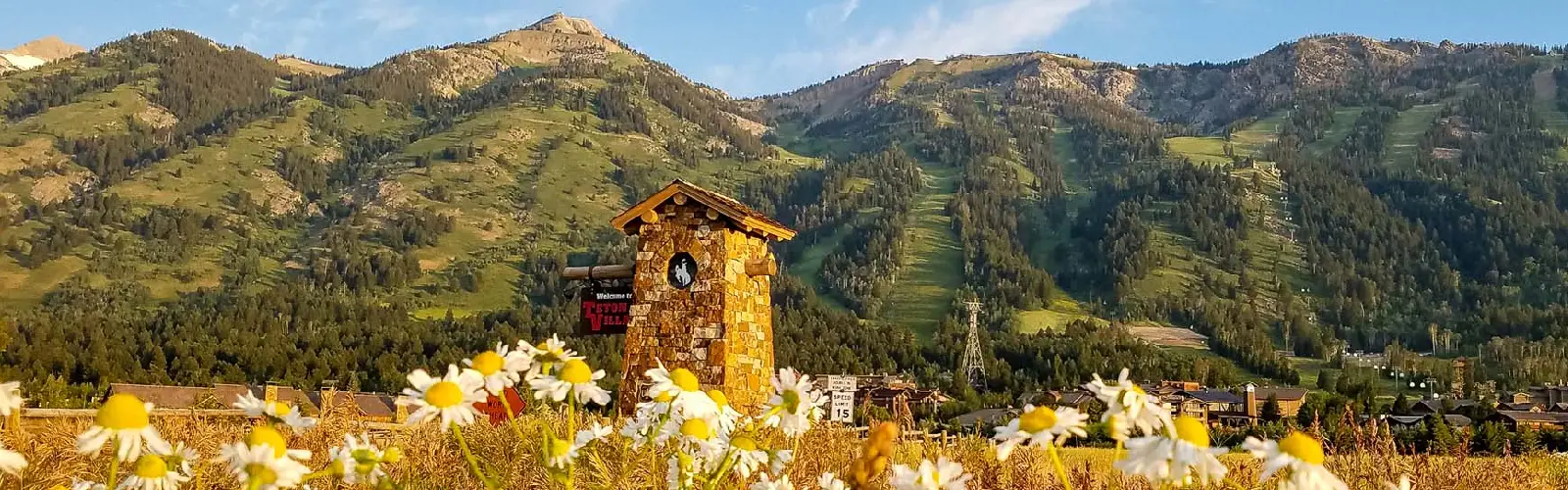 The Teton Village welcome sign behind flowers near the entrance of Teton Village, WY.